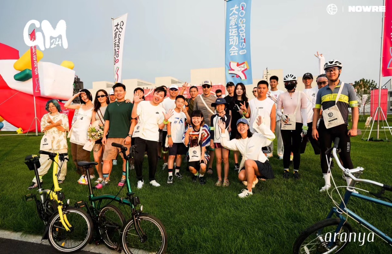 A group photograph on a golf course beside golf bags and event signage