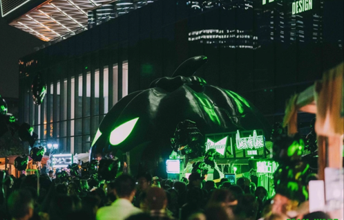 Visitors gathering around the glowing pumpkin installation