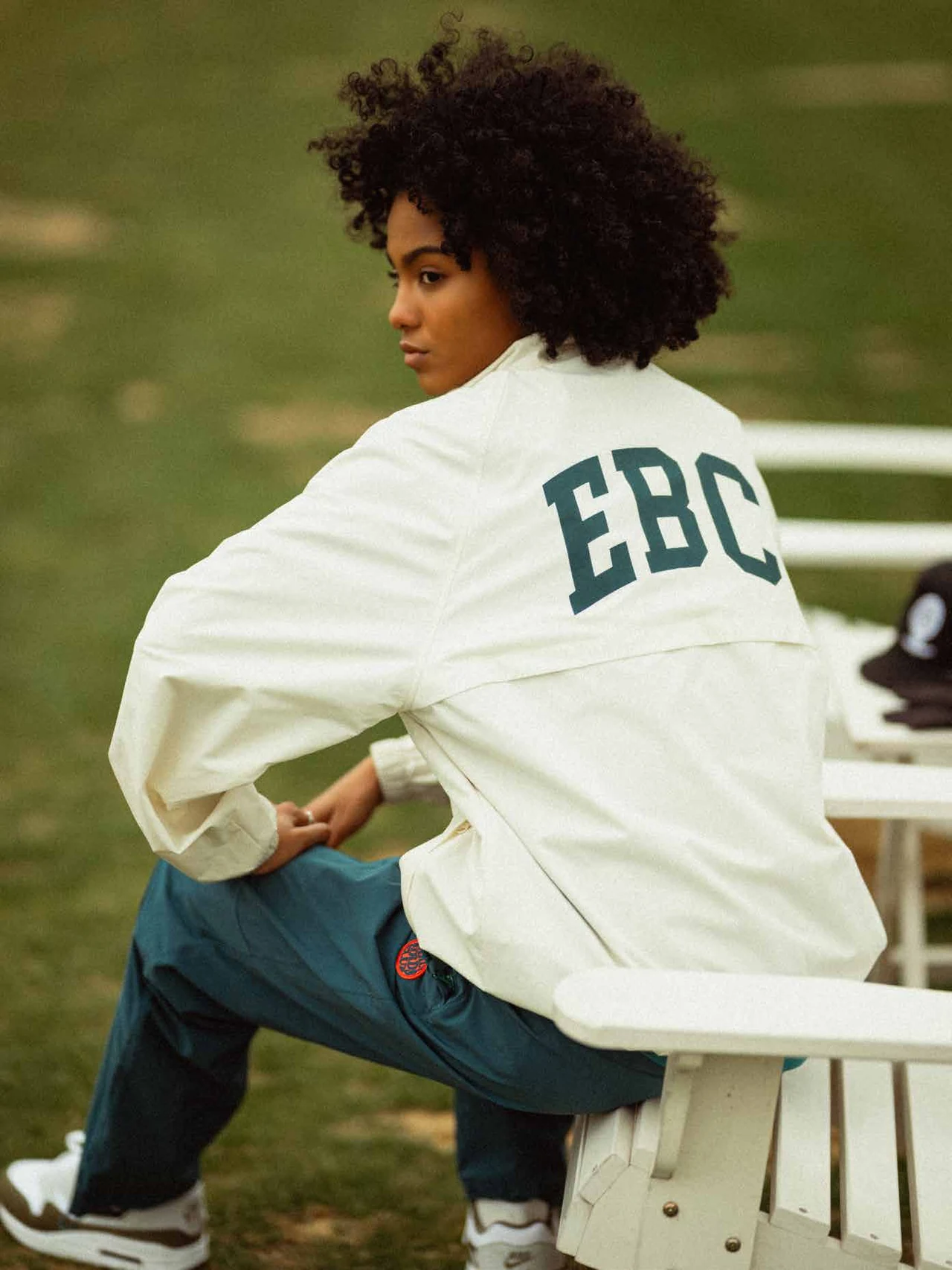 Model seated in a white EBC jacket, looking back toward the camera