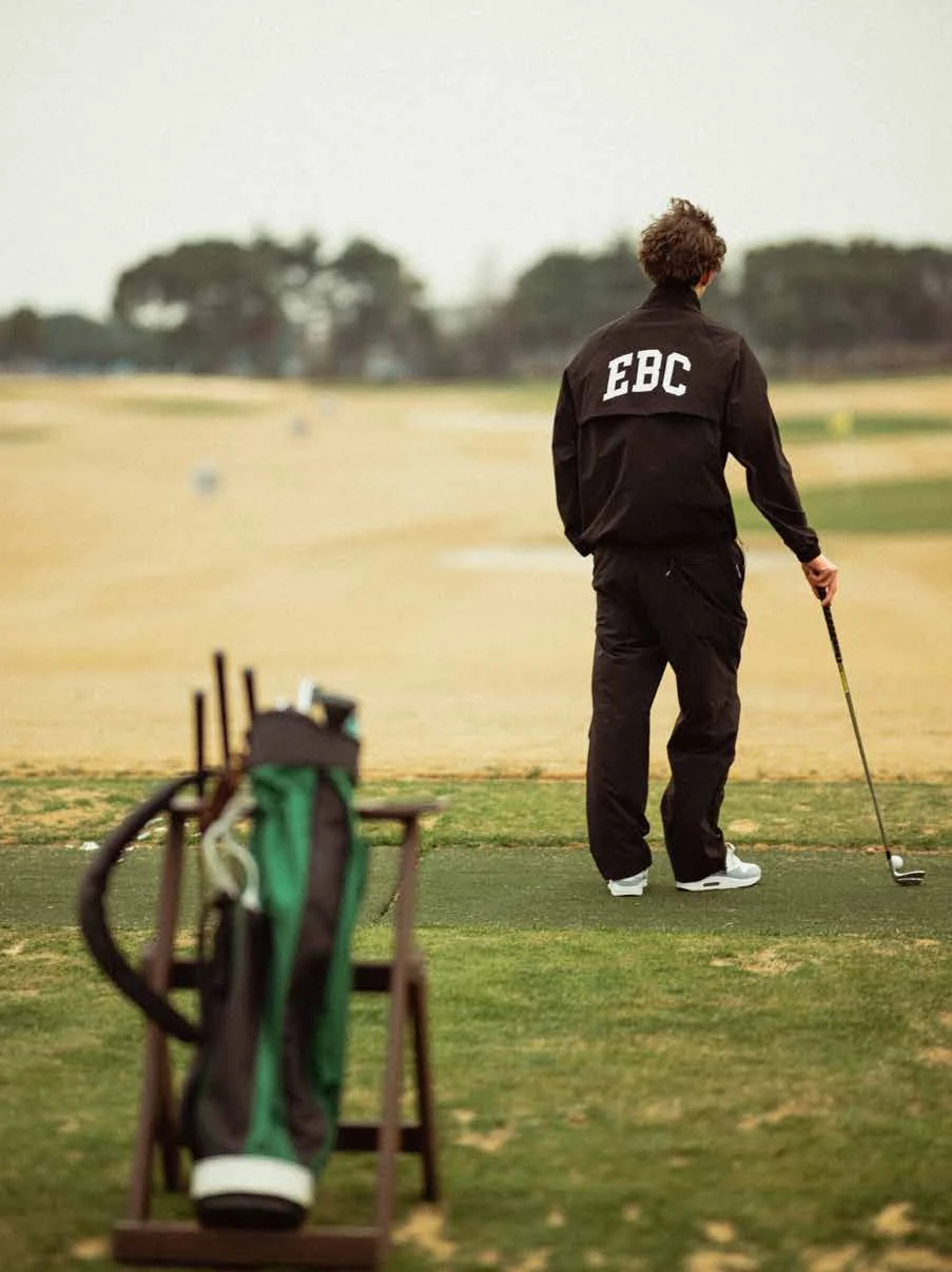 Golfer in black EBC clothing beside a golf bag on the course